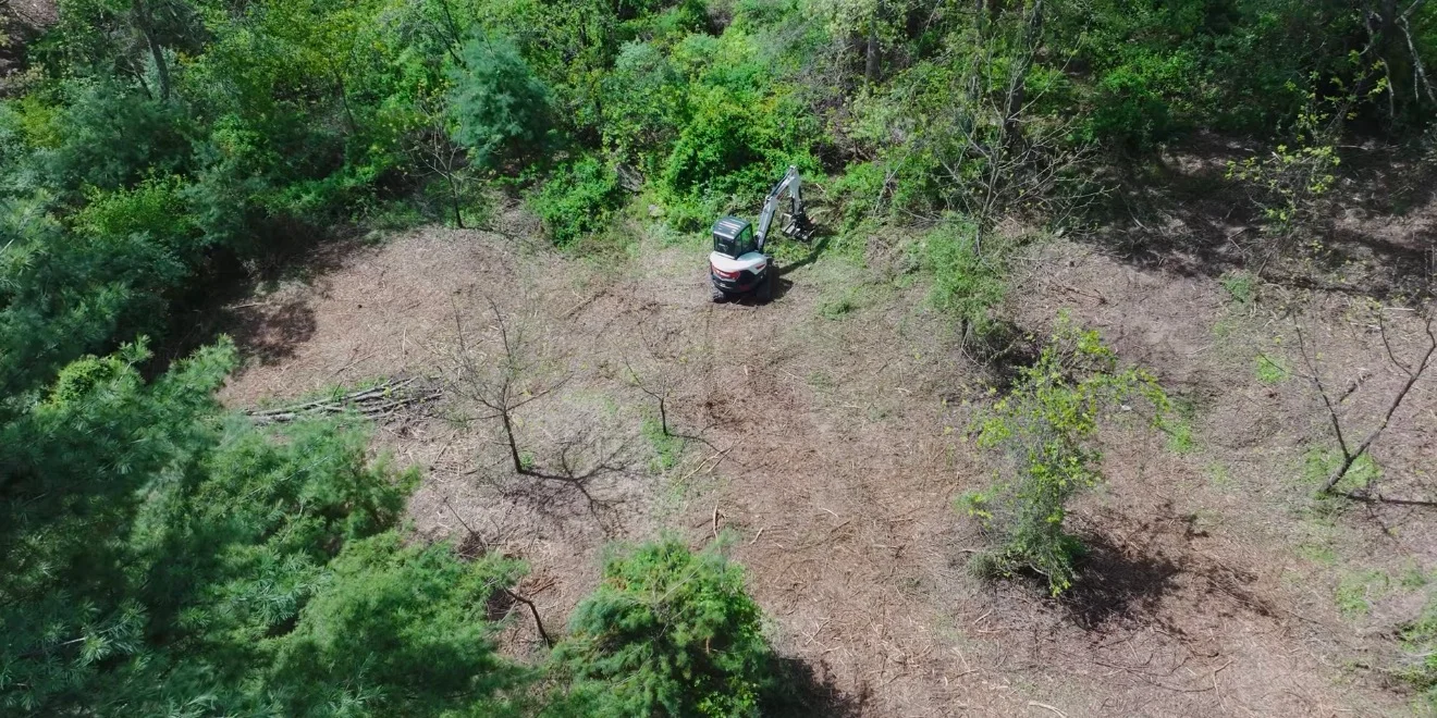 Aerial view of cleared wooded land with brush hogging equipment and selective tree removal